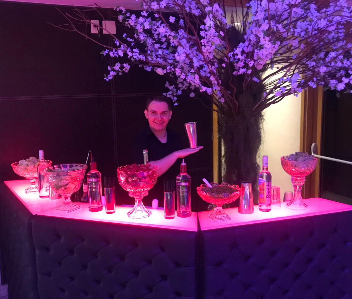 Bar cenográfico da KingFlair iluminado em tons neon durante um evento